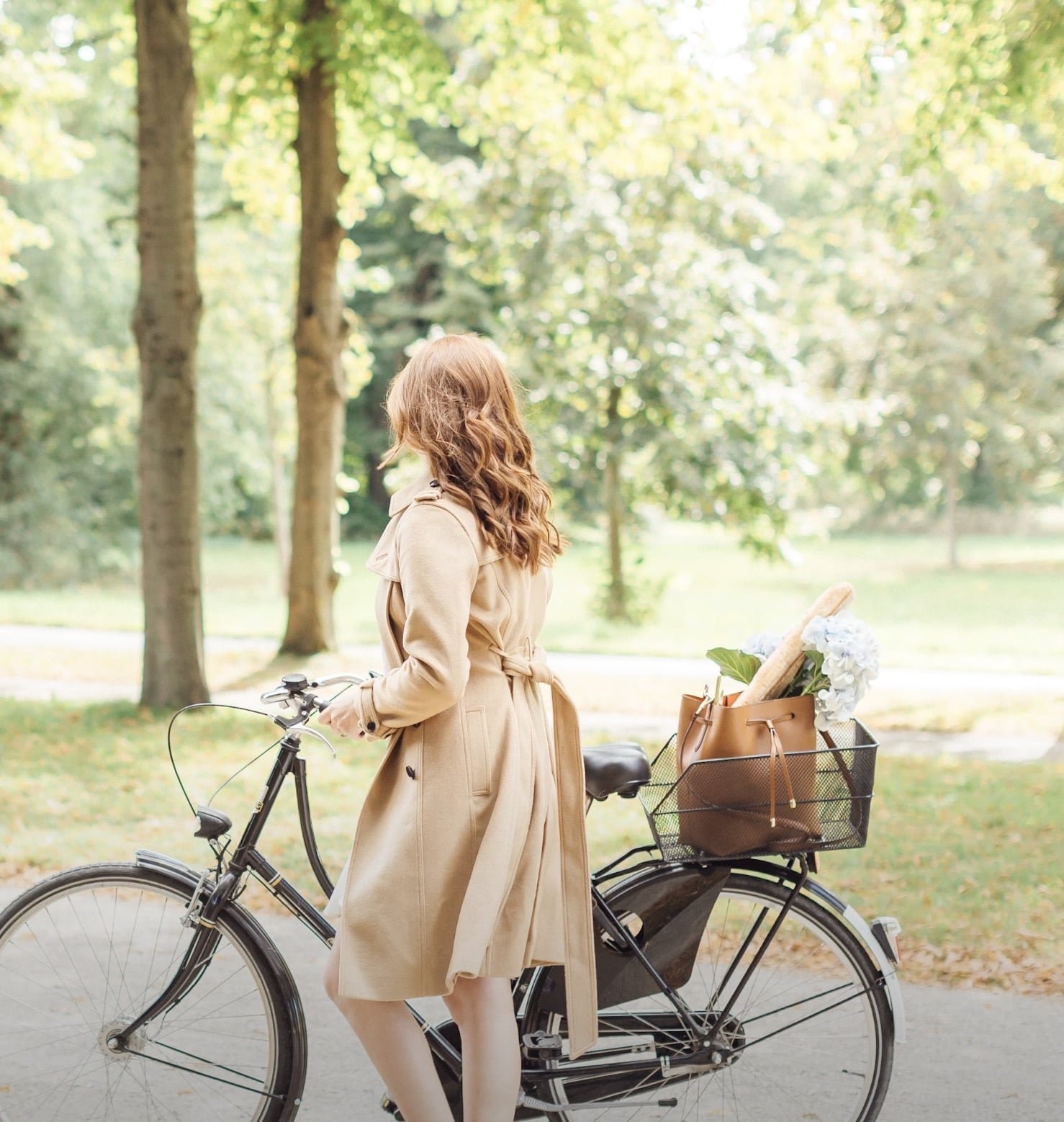 Paige wheeling her bike in the park looking away from the Camera